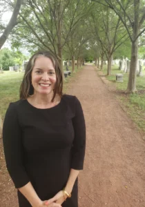 Photo of Lily Buerkle standing on a path in a cemetary.